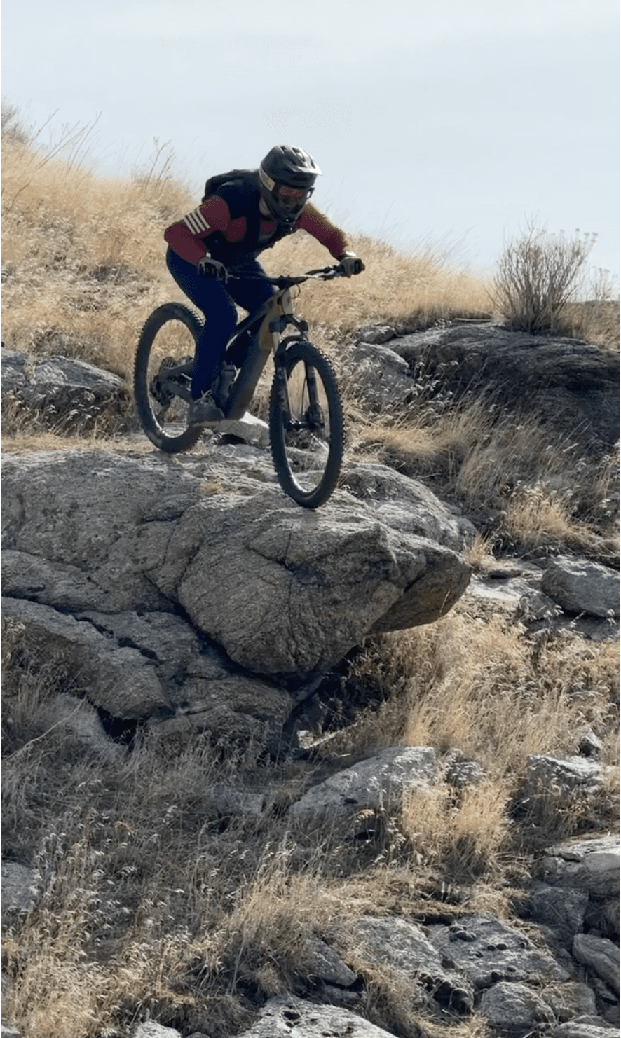 Chris riding off a rock feature on a mountain bike trail